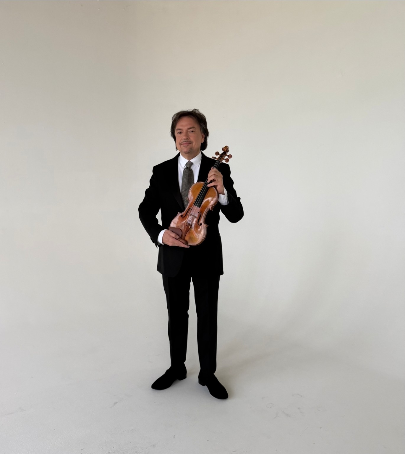 Sergej Krylov holding his violin, full-length portrait